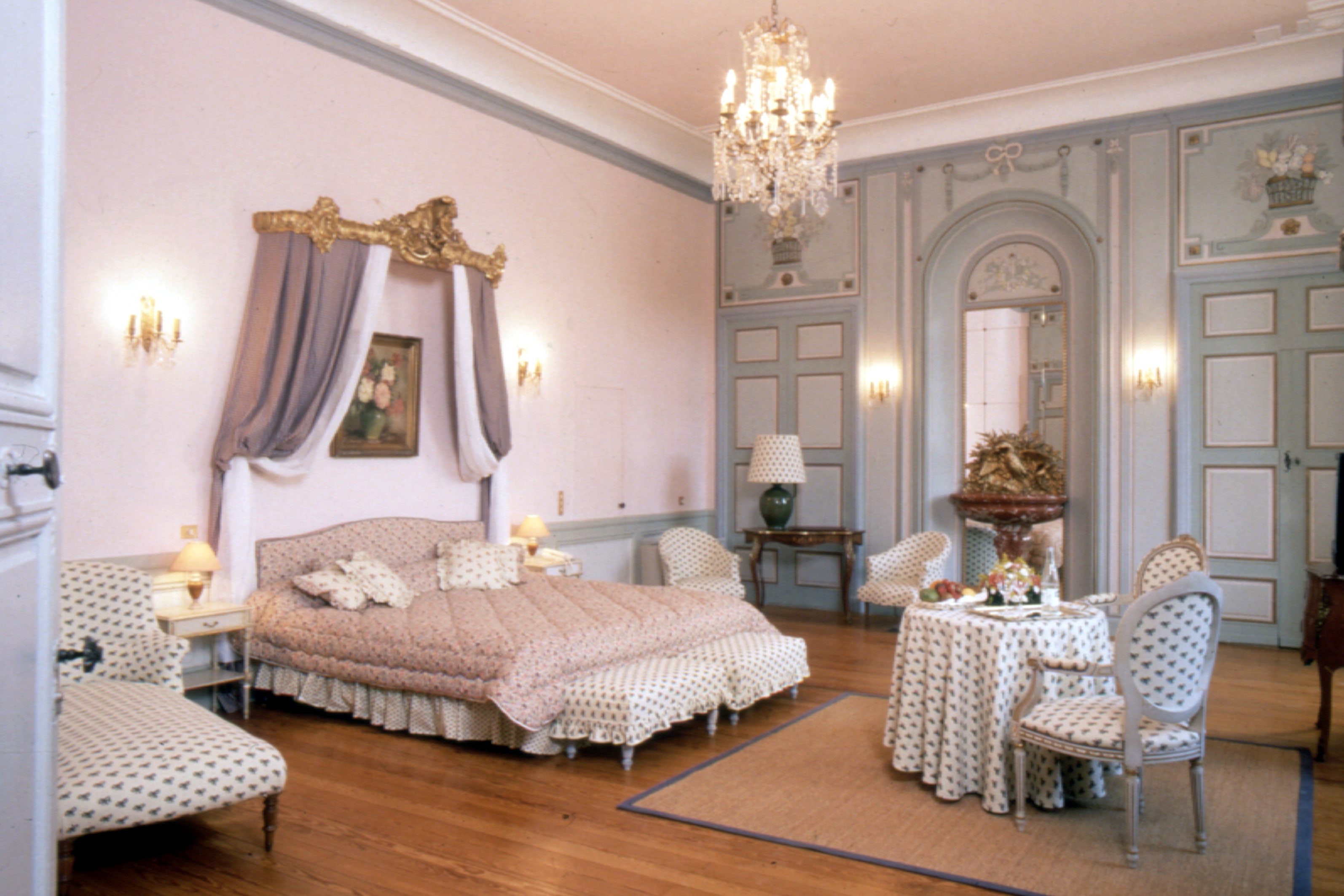 Chambre style baroque avec tissus provençaux et sol en parquet bois.